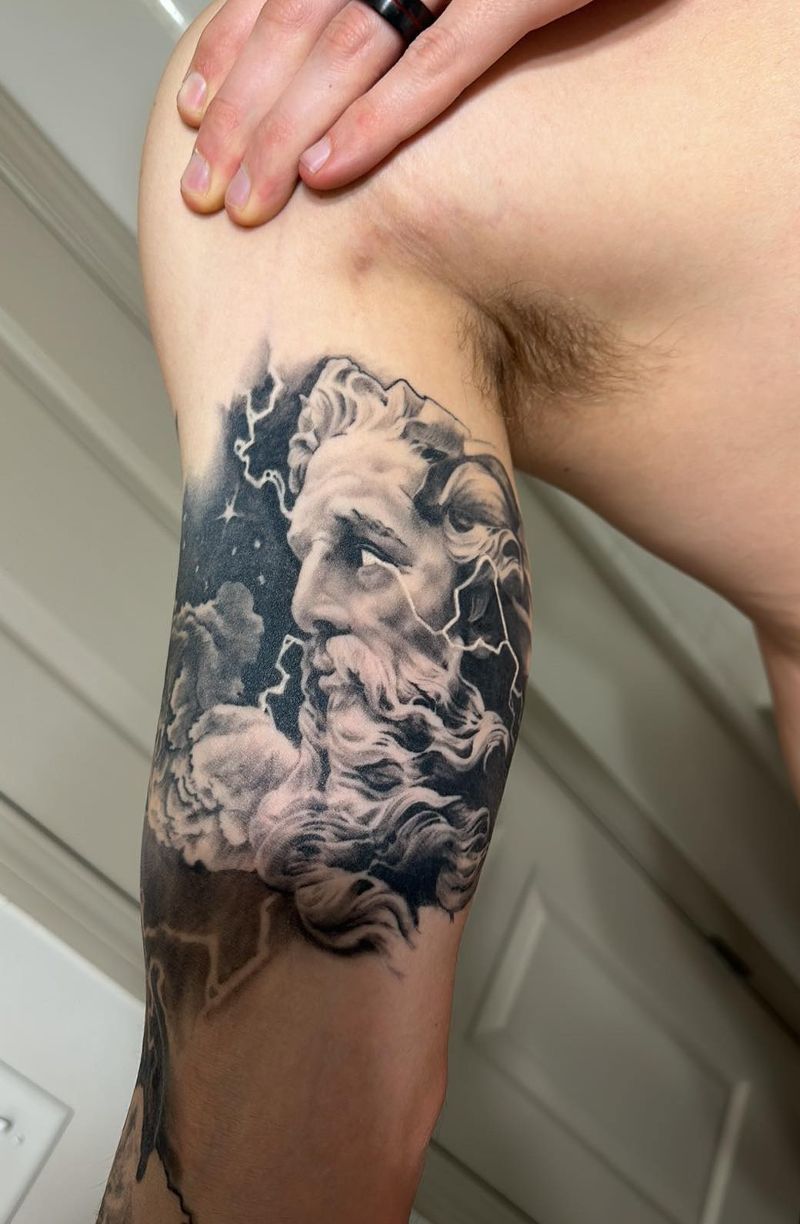 A man has a tattoo of a statue on his arm
