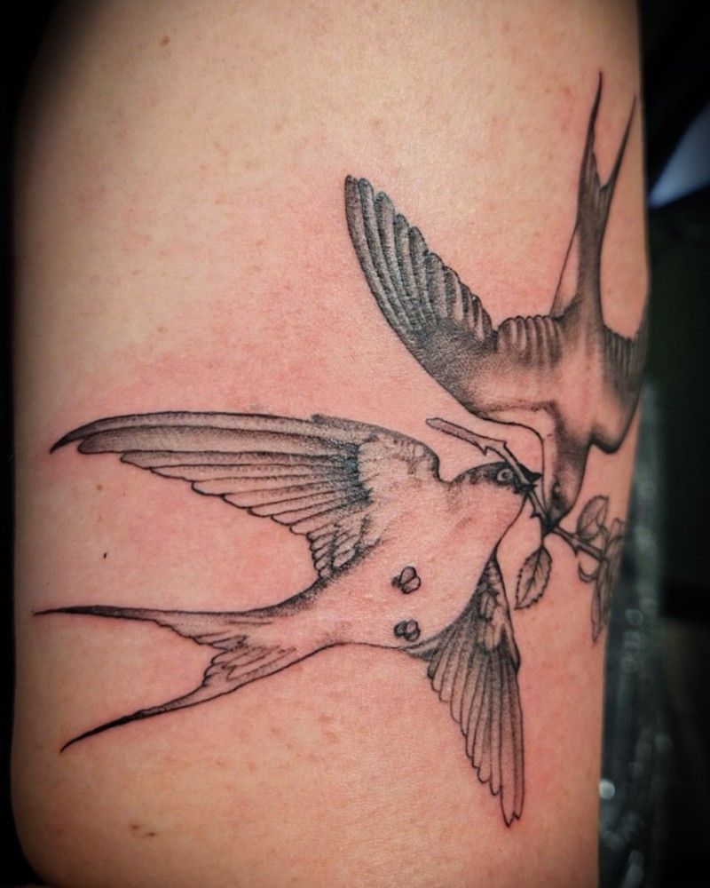 A tattoo of two swallows on a person 's arm