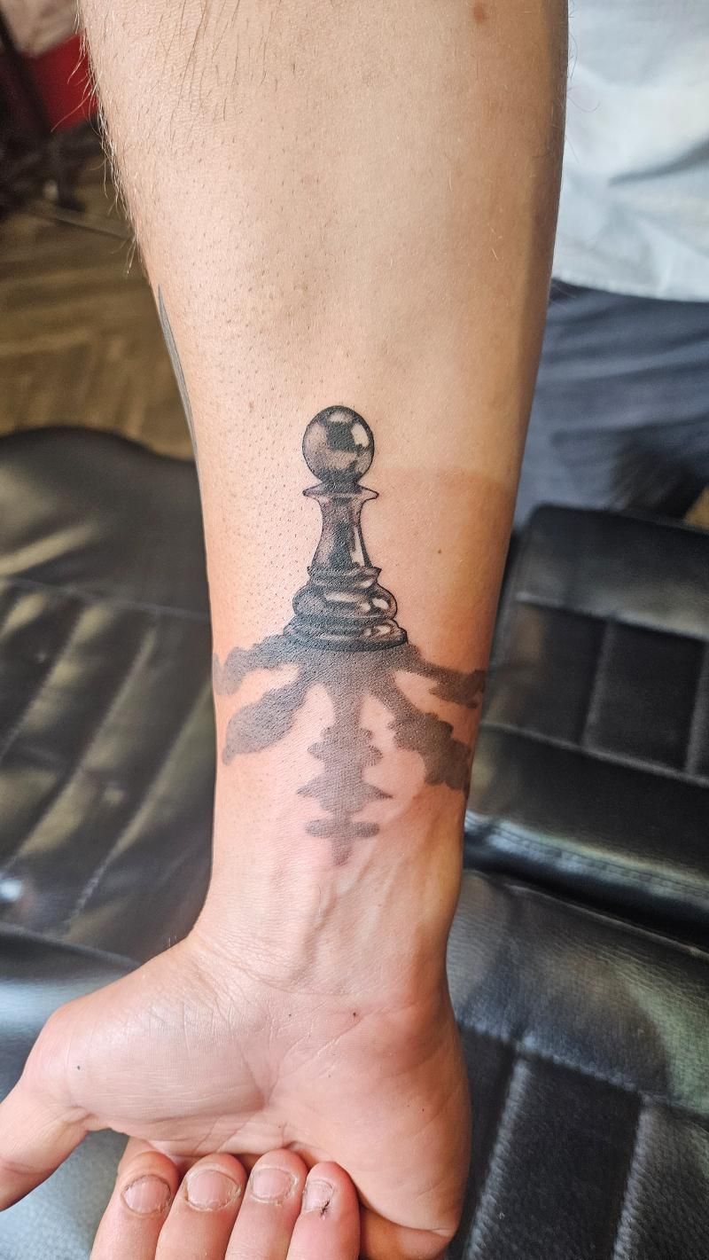 A man has a tattoo of a chess piece on his wrist.