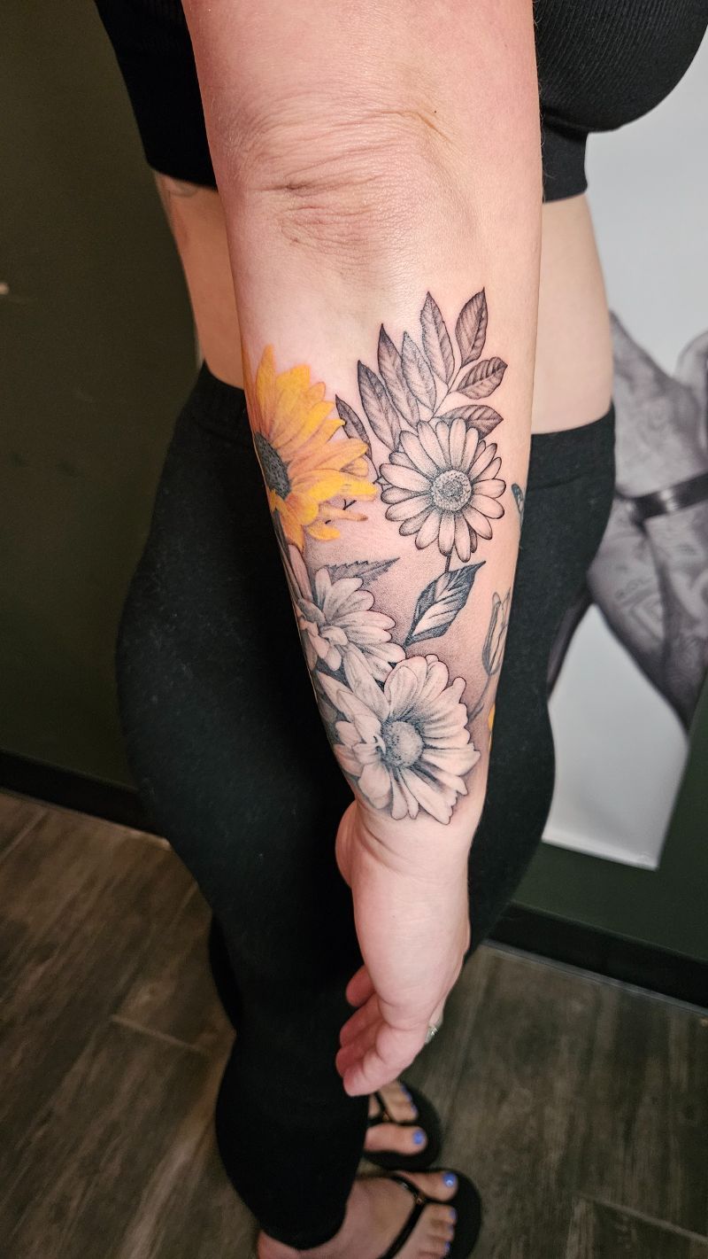 A woman has a tattoo of flowers on her forearm.