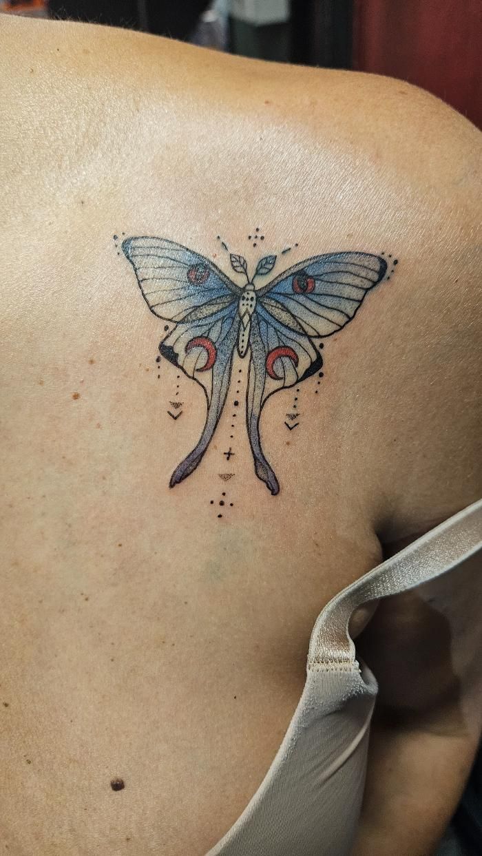 A woman has a blue butterfly tattoo on her shoulder.