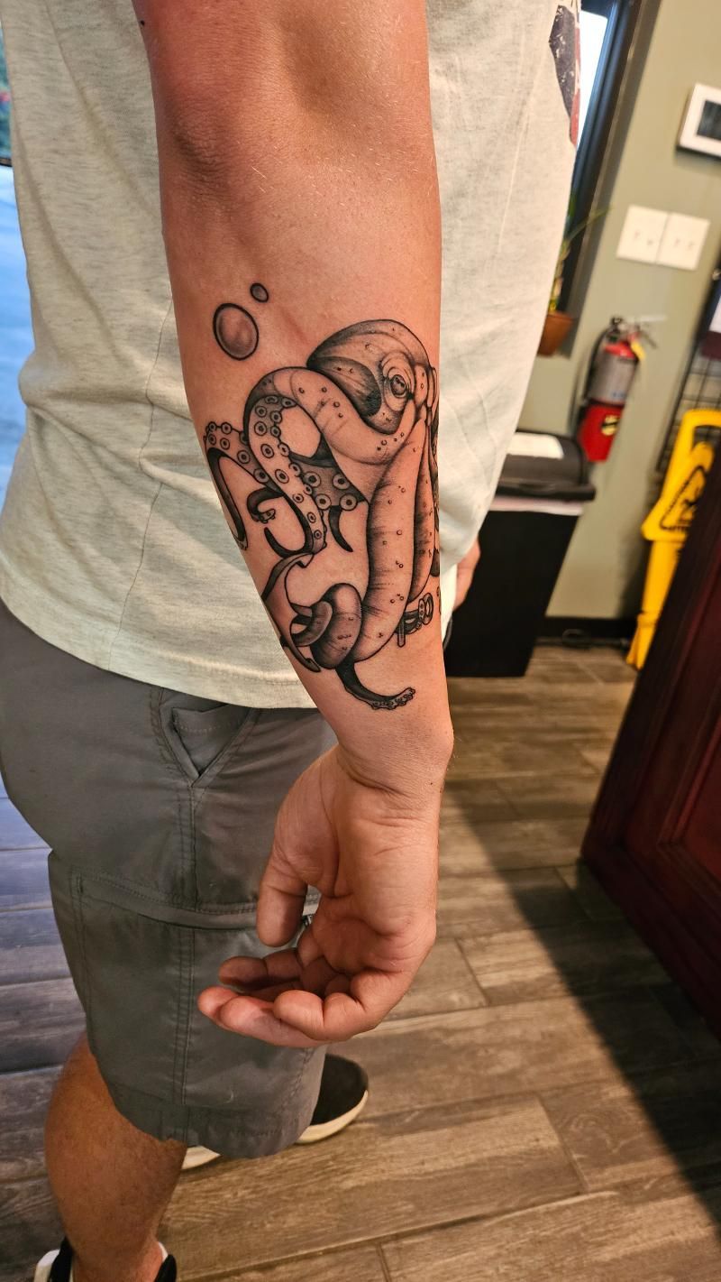 A man has a tattoo of an octopus on his forearm.