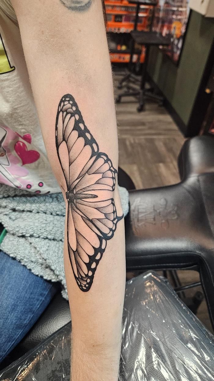 A woman has a tattoo of a butterfly on her arm.