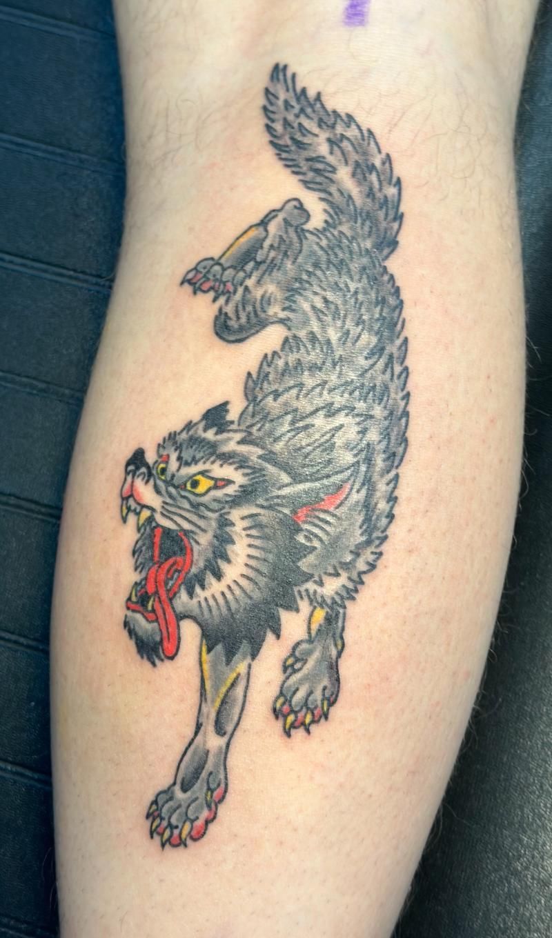A tattoo of a black cat on a person 's leg
