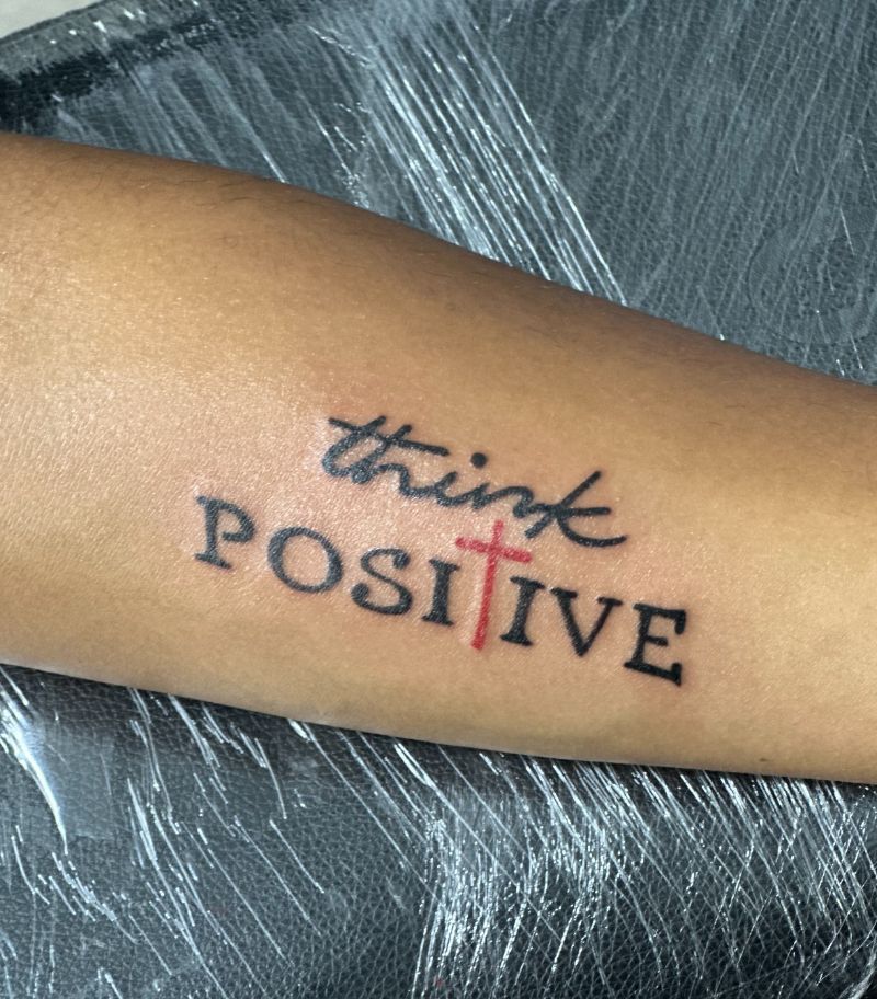 A tattoo on a person 's arm that says think positive