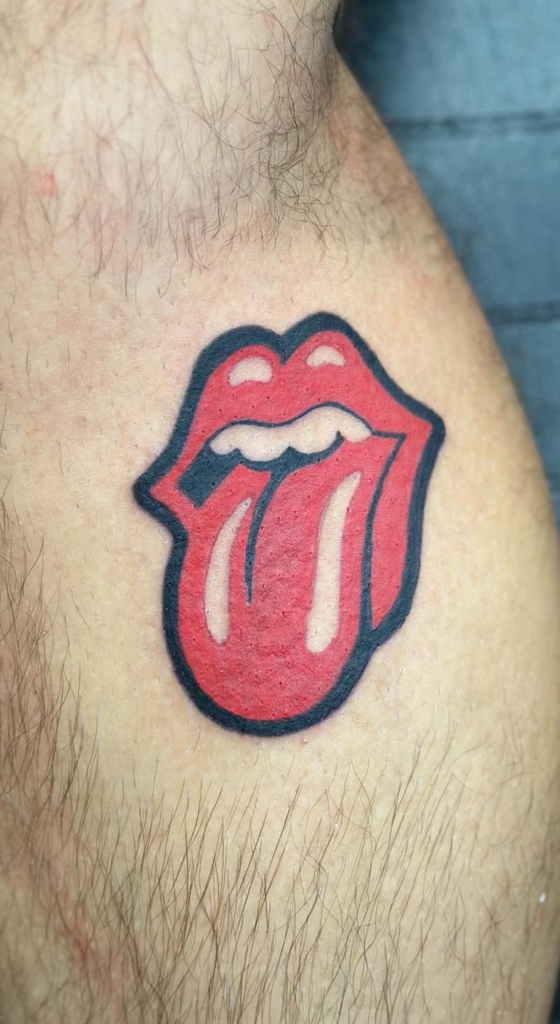 A man has a tattoo of the rolling stones logo on his arm.
