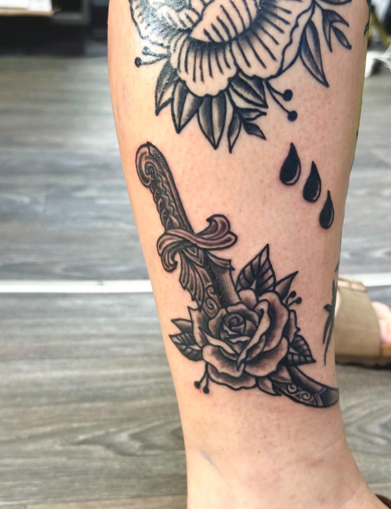 A person has a tattoo of a rose and a dagger on their leg