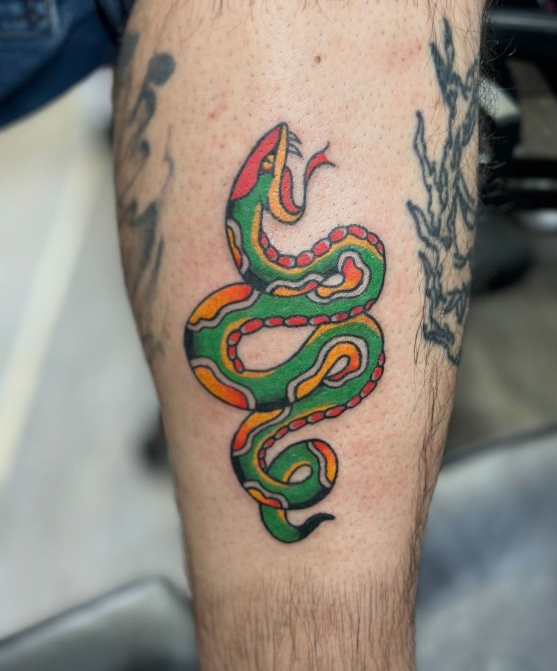 A man has a tattoo of a snake on his leg