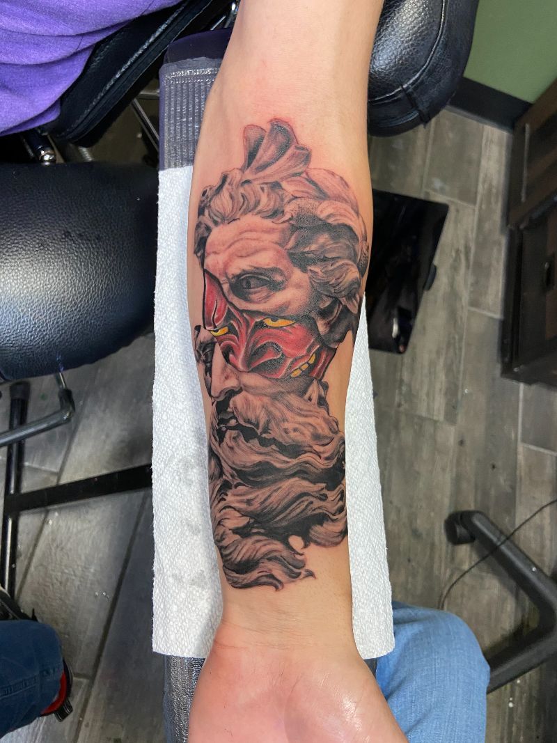 A person has a tattoo of a statue on their forearm.