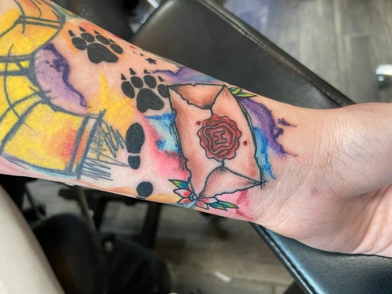 A person has a tattoo of an envelope with a rose on it