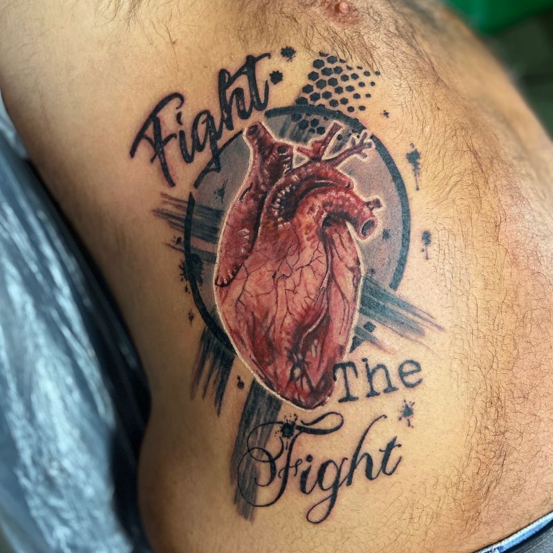 A man has a tattoo on his side that says fight the fight