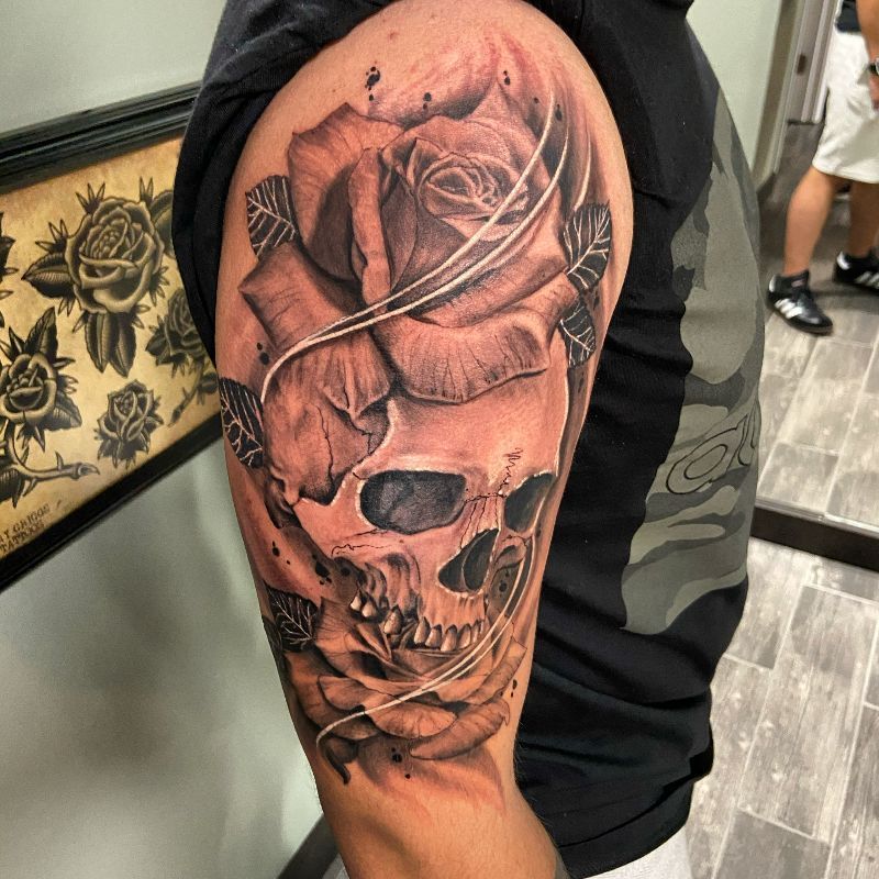 A man has a tattoo of a skull and a rose on his arm