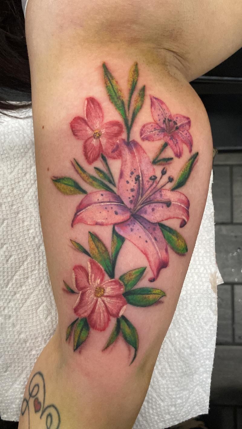 A woman has a tattoo of pink flowers on her arm.