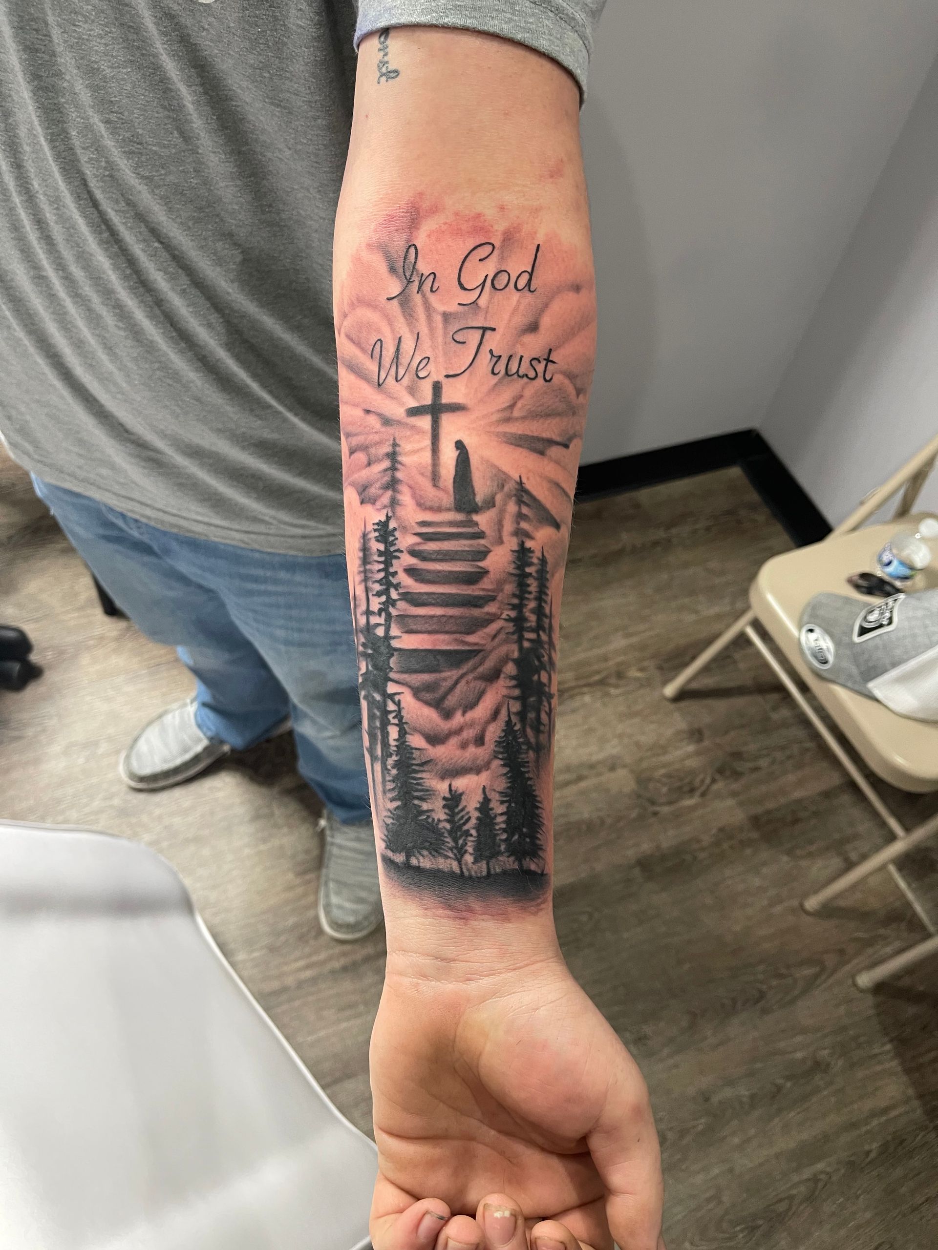 A man has a tattoo on his forearm that says `` you god we trust ''.