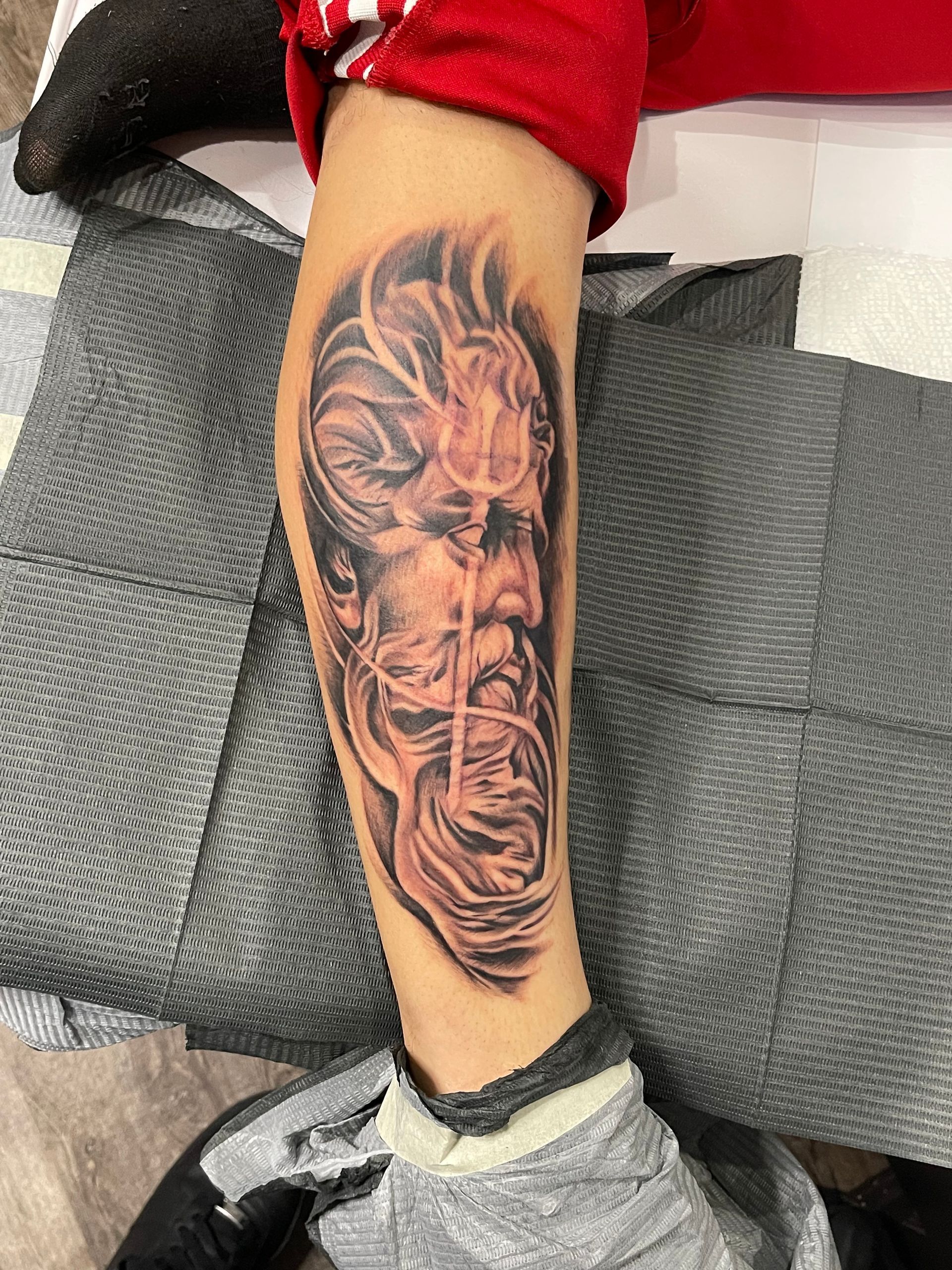 A person has a tattoo of a man with a beard on their leg.