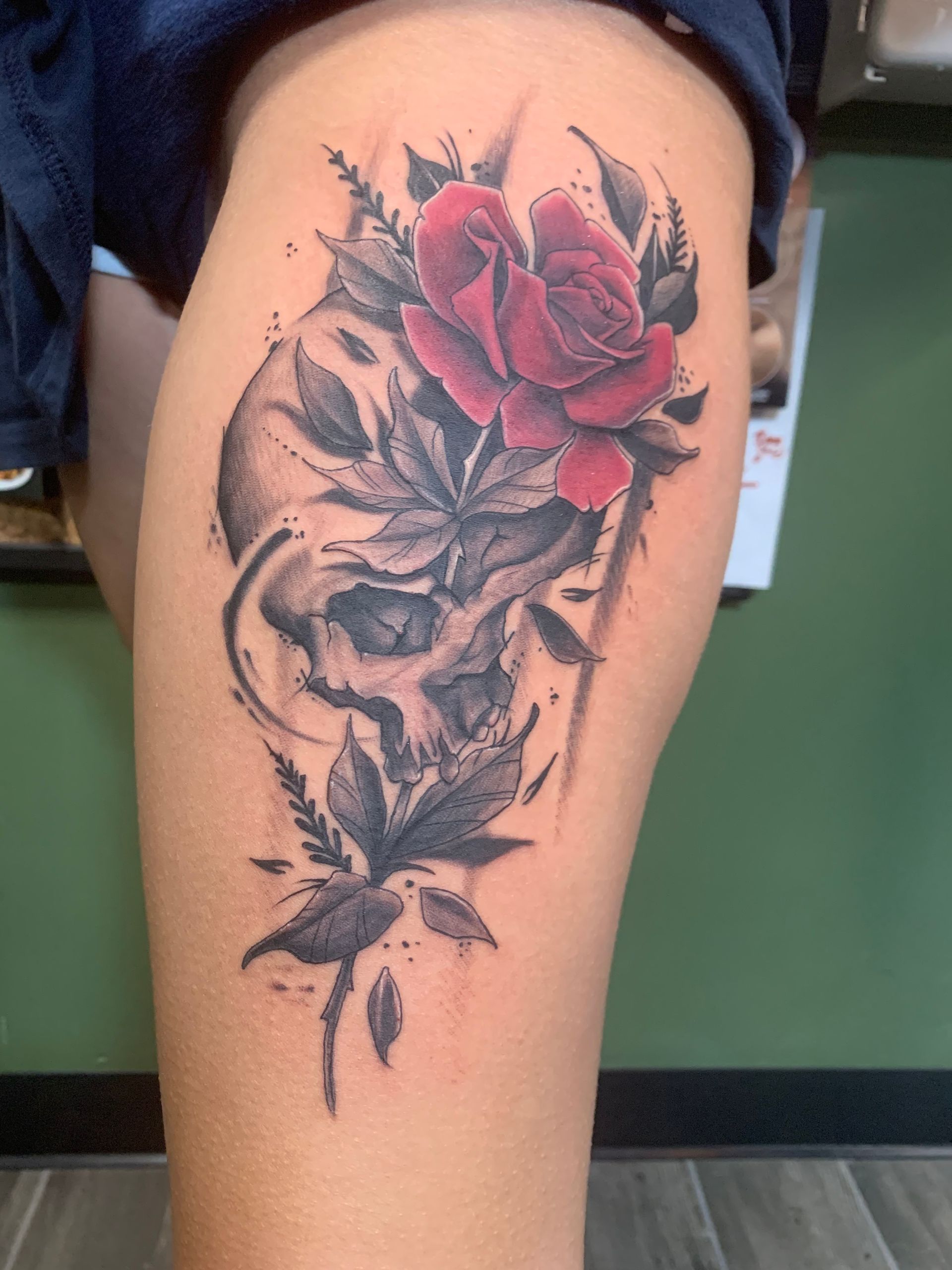 A woman has a tattoo of a skull and a rose on her leg