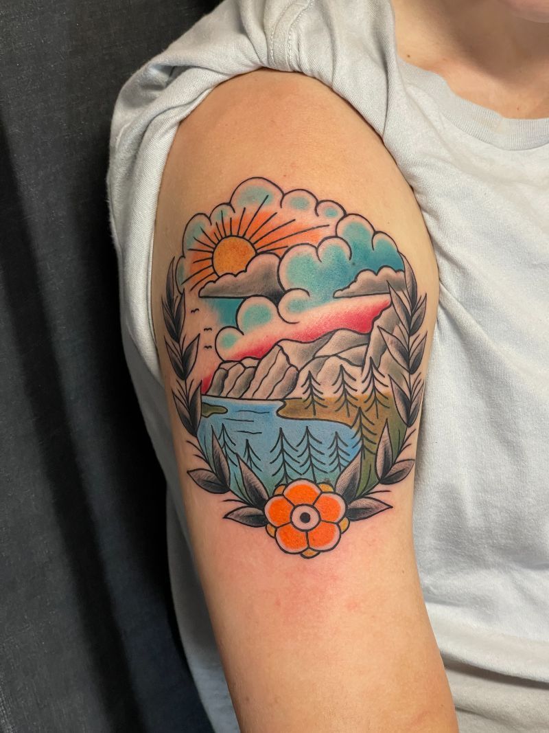 A person has a tattoo of a mountain and a lake on their arm.