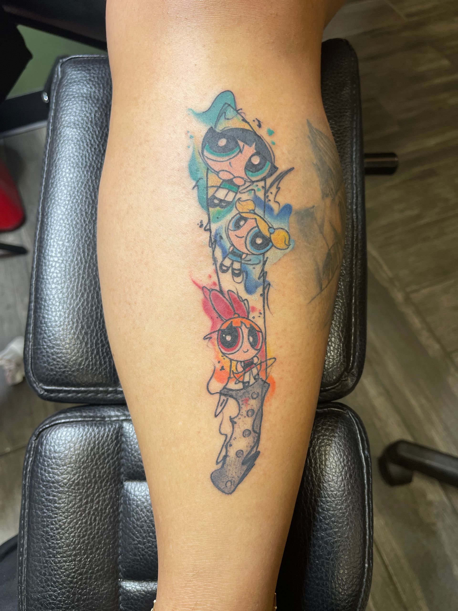 A woman has a tattoo of the powerpuff girls on her leg
