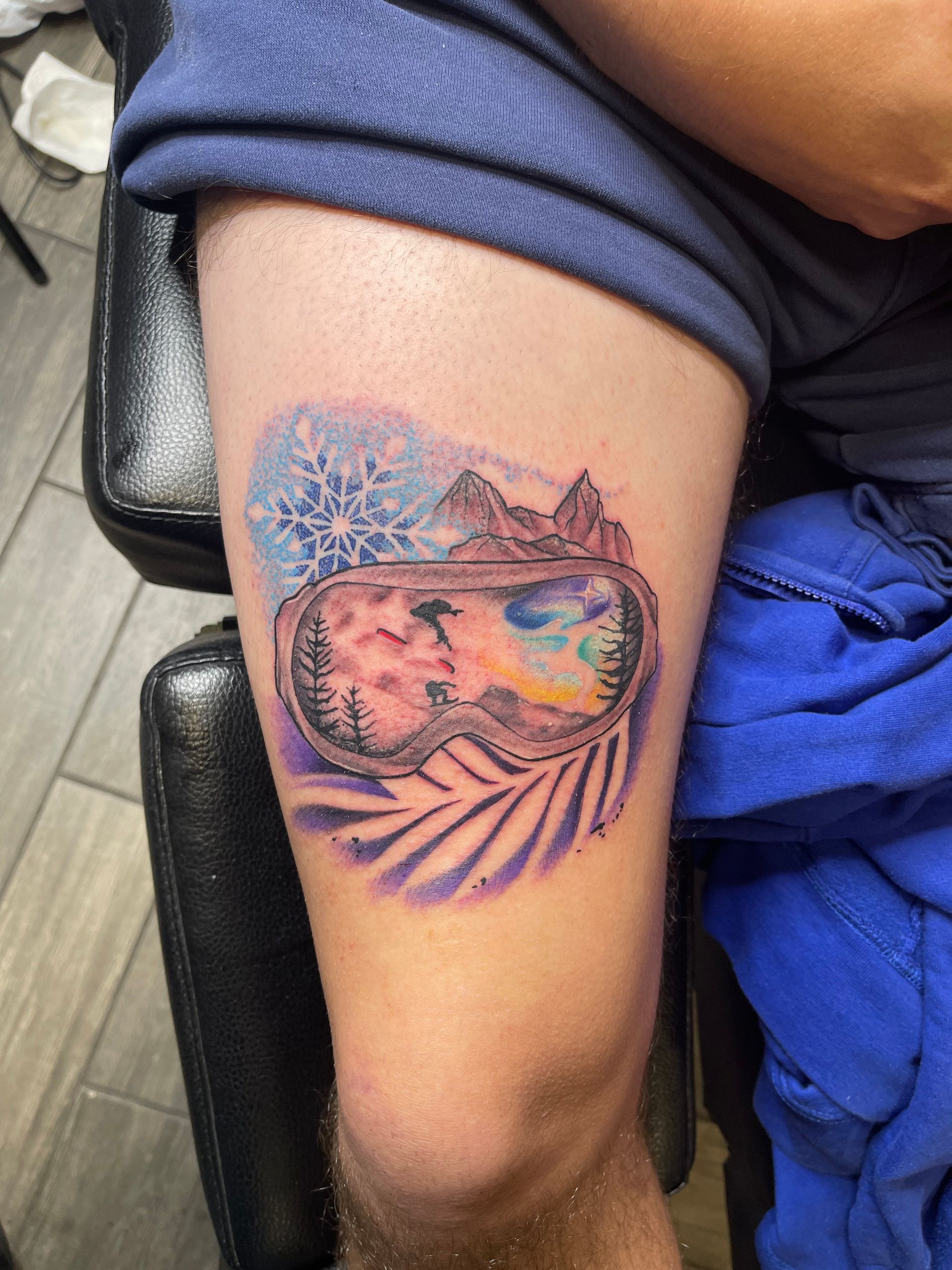 A person has a tattoo of a ski goggles on their leg.