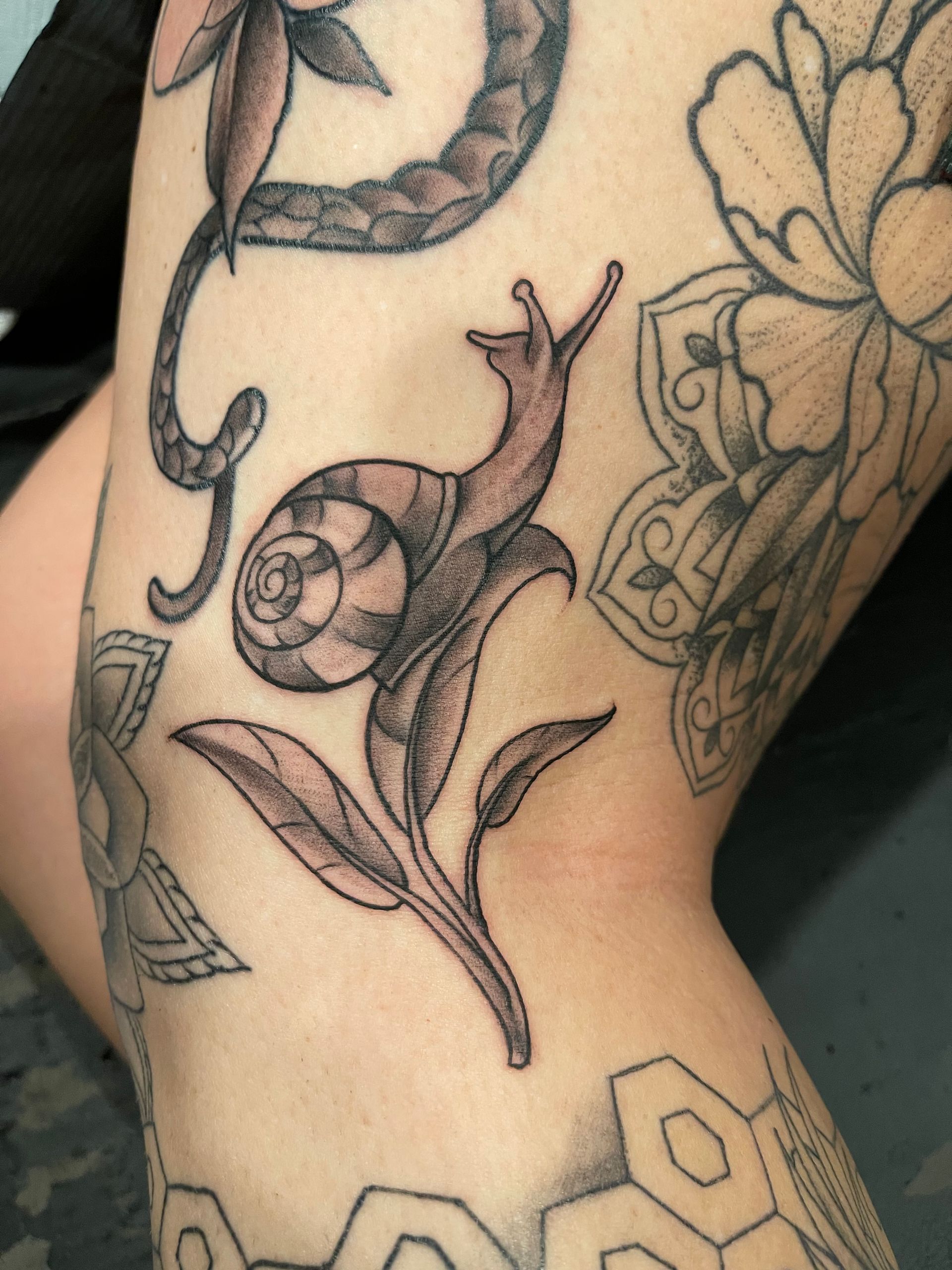 A woman has a tattoo of a snail on her leg