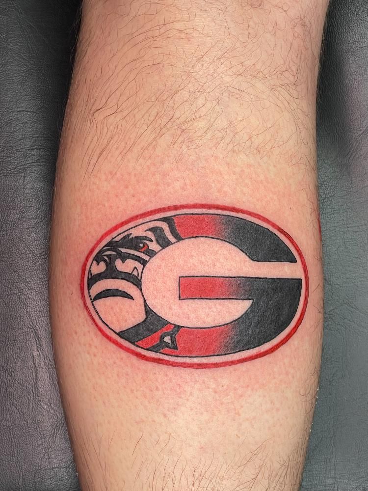 A person has a tattoo of the georgia bulldogs logo on their leg.