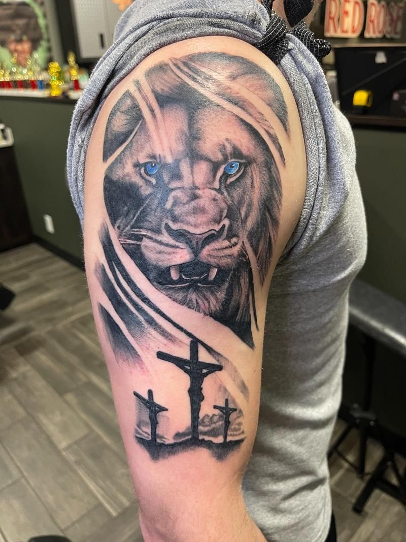 A man has a tattoo of a lion and a cross on his arm.