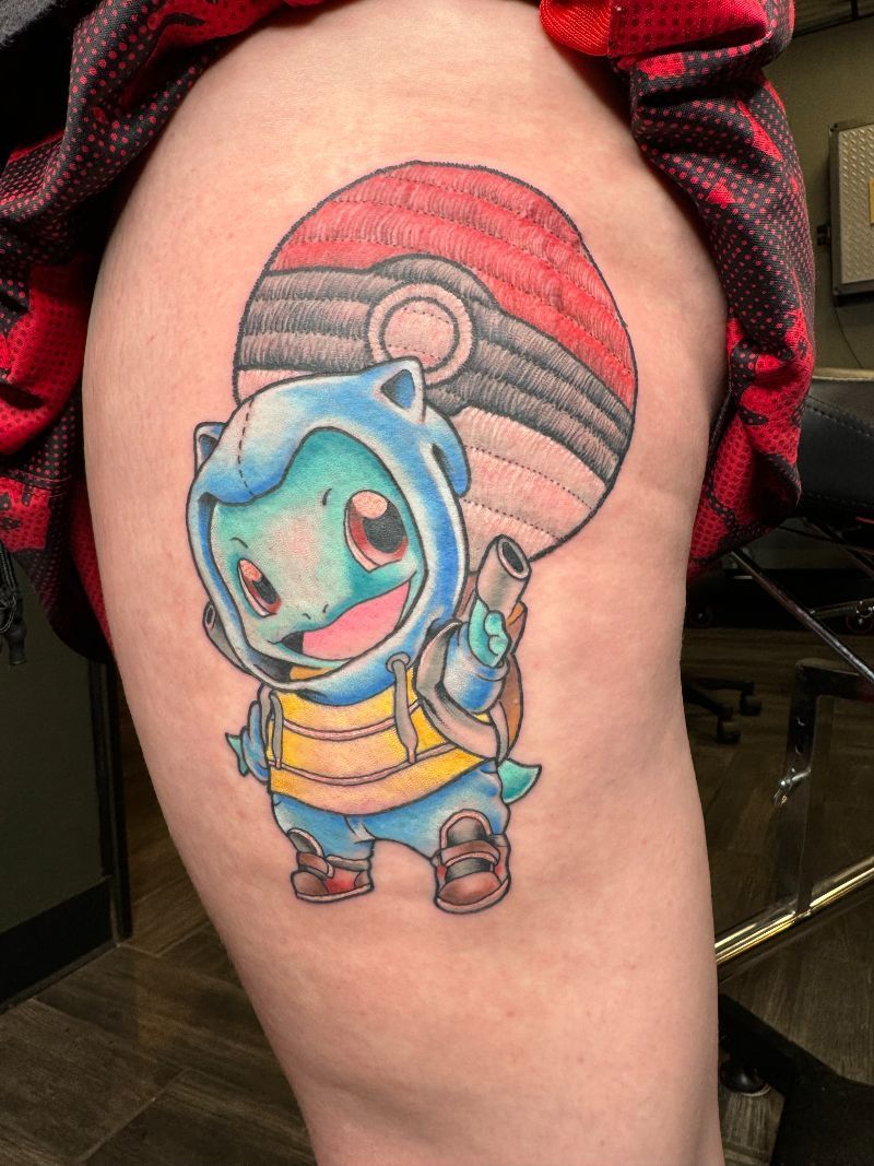 A person has a tattoo of squirtle holding a pokeball on their thigh.