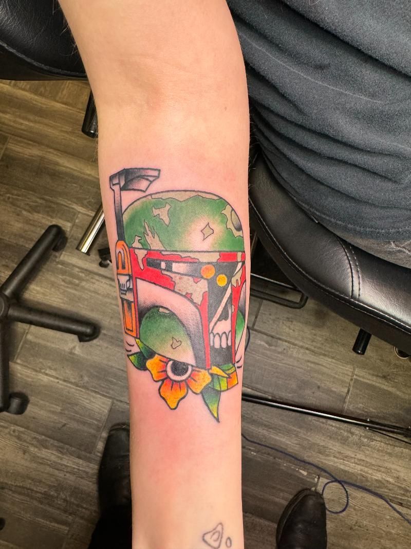 A person has a boba fett tattoo on their forearm.