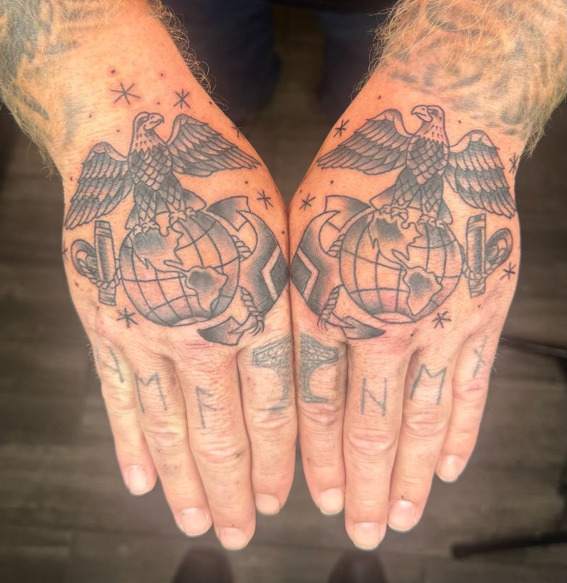 A man has a tattoo of a globe and eagle on his hands