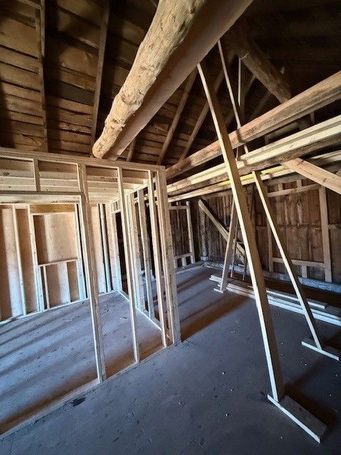 Unfinished attic with exposed wooden framing, beams, and slanted roof trusses.