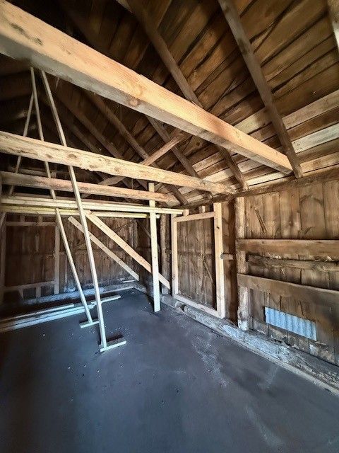 Bare wooden attic with exposed beams, rafters, and a dark floor under construction