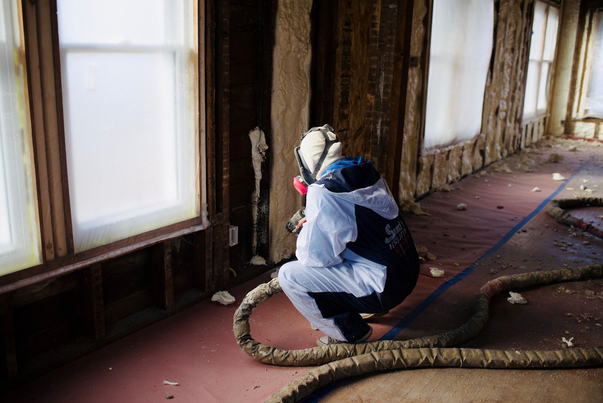 A person is spraying insulation on a wall in a room.