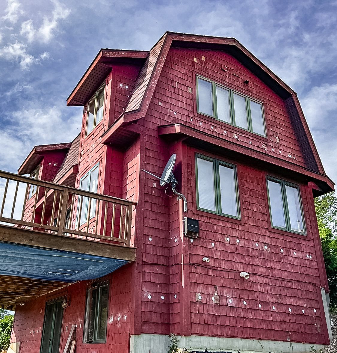 A red house with a balcony and satellite dish on the side