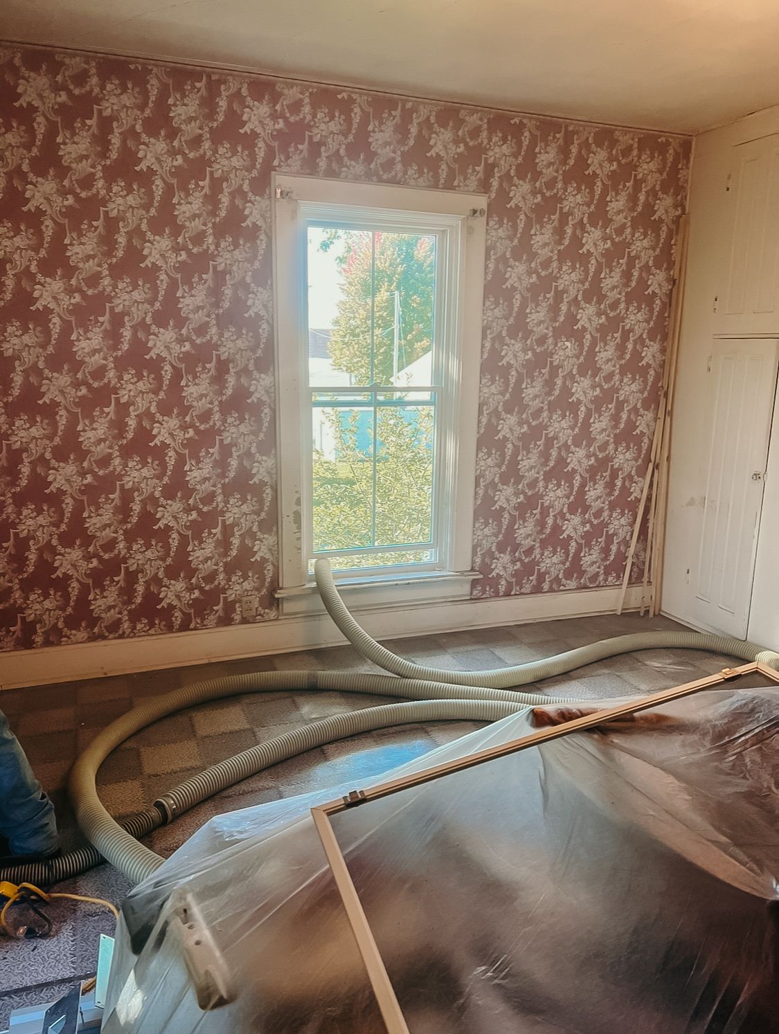 A room with a window and a vacuum hose in it.