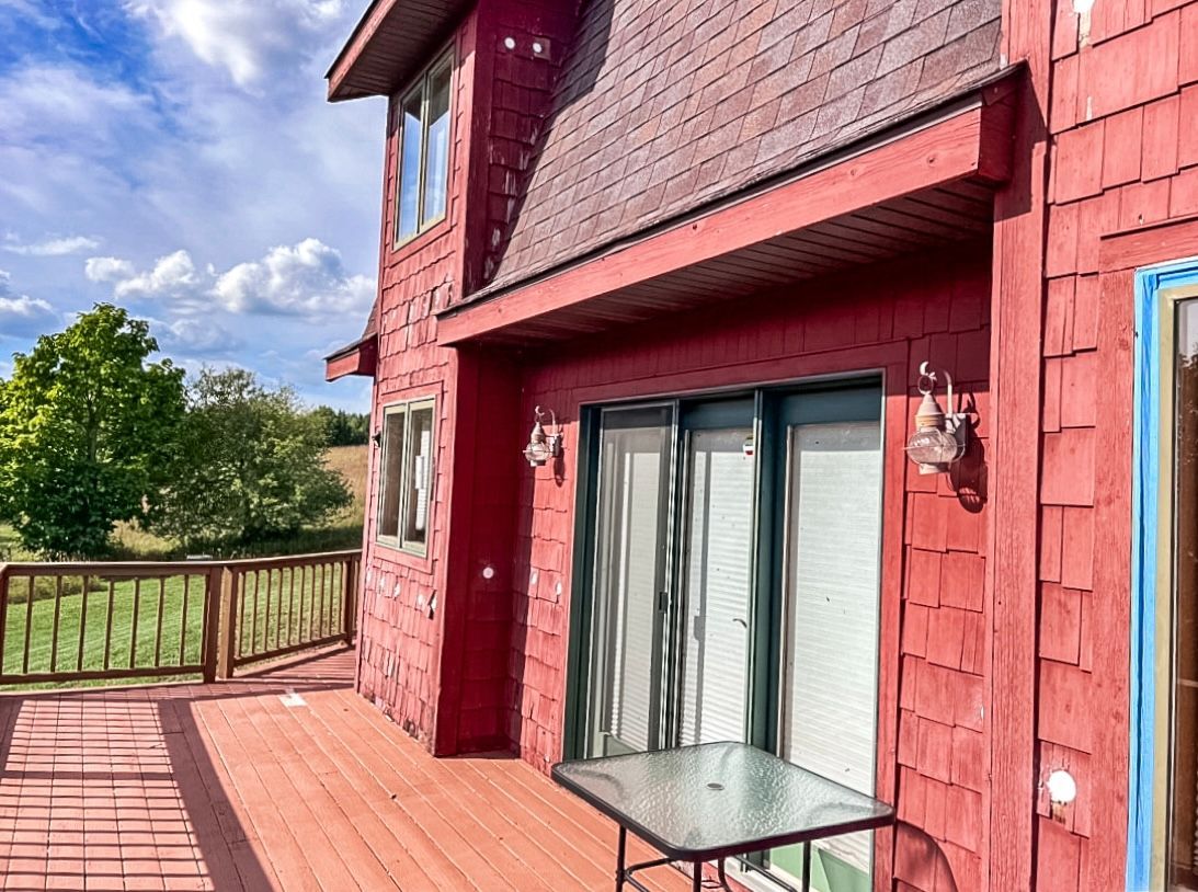 A red house with a large deck and sliding glass doors.