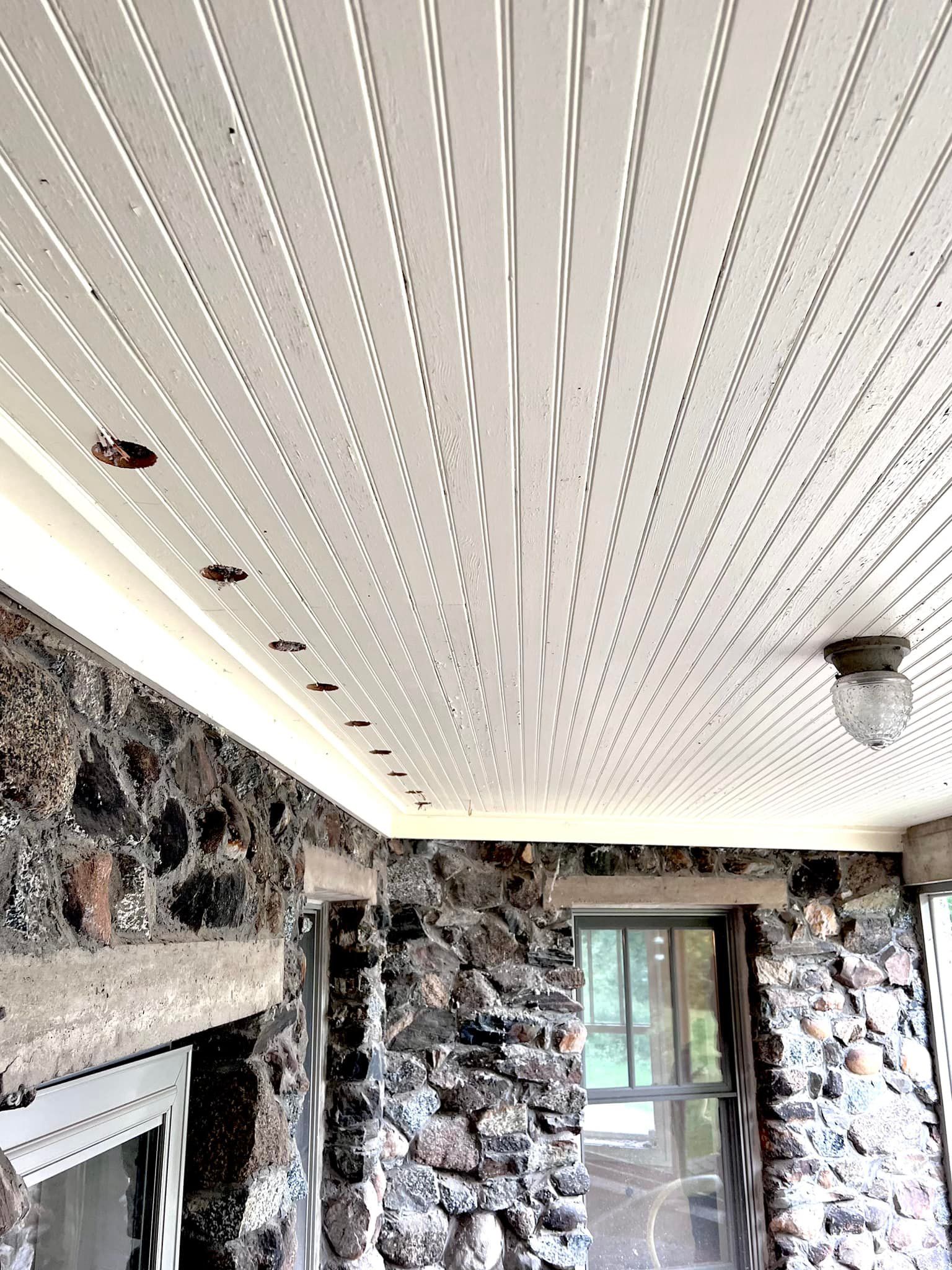 The ceiling of a room with a stone wall and a white ceiling.