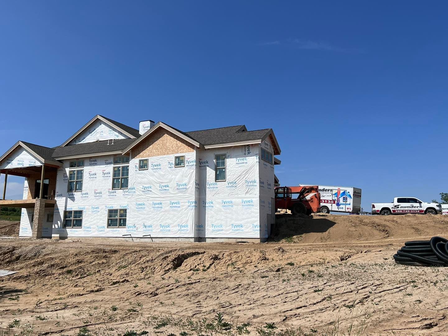 A large house is being built on top of a dirt hill.