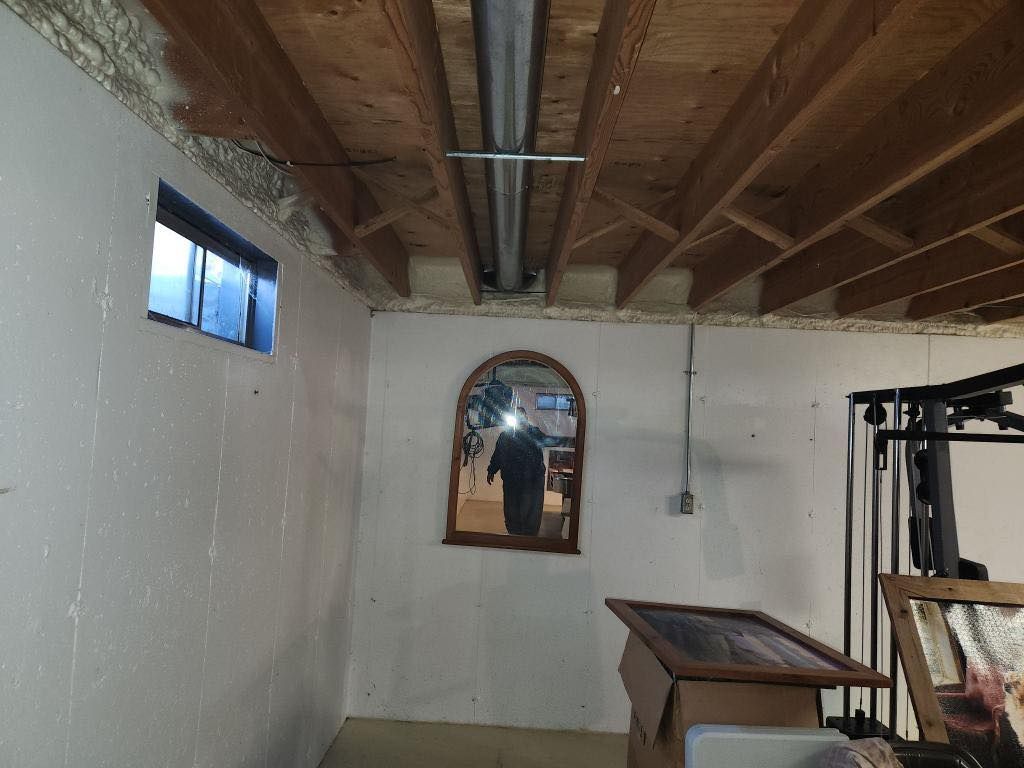 A room with a mirror on the wall and a window.