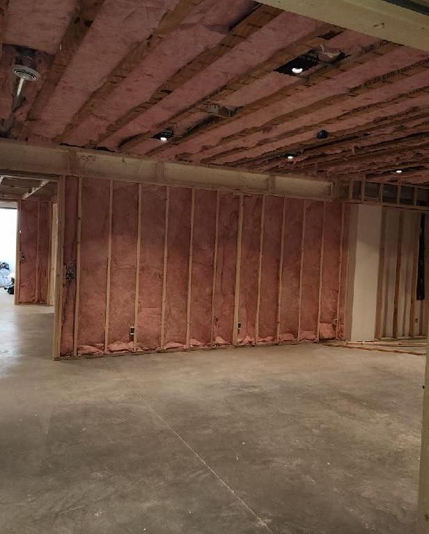 A basement under construction with insulation on the walls and ceiling.