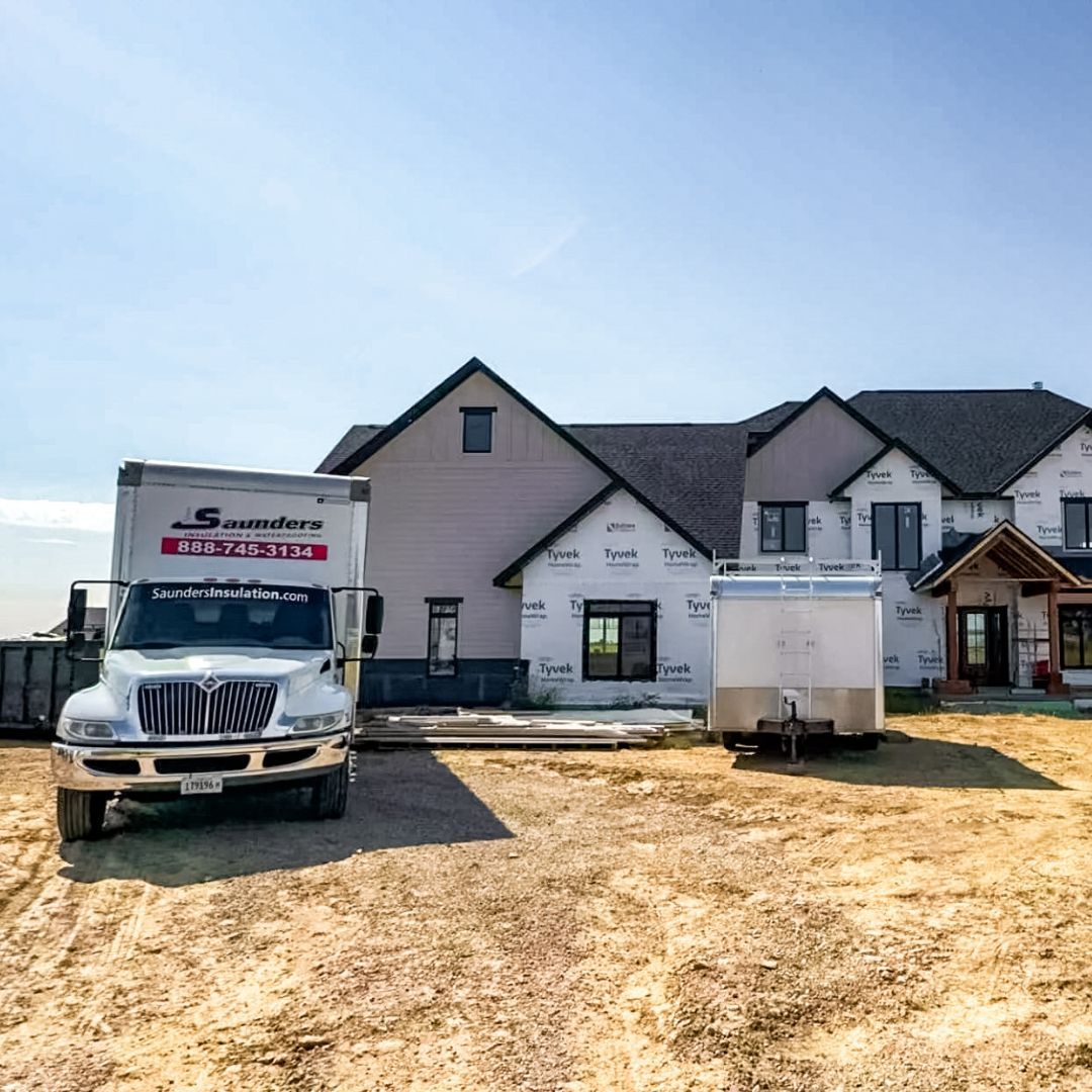 A truck is parked in front of a large house under construction.