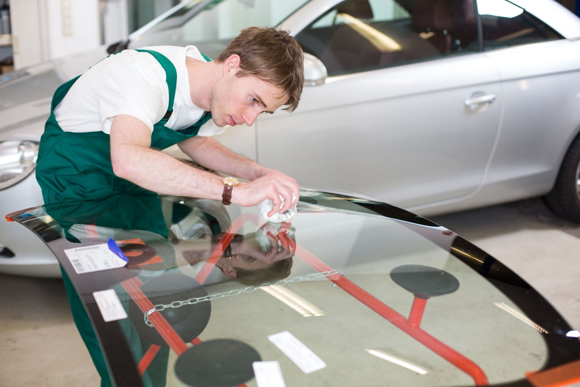 Mechanic repairing a car windshield with a power tool in a garage