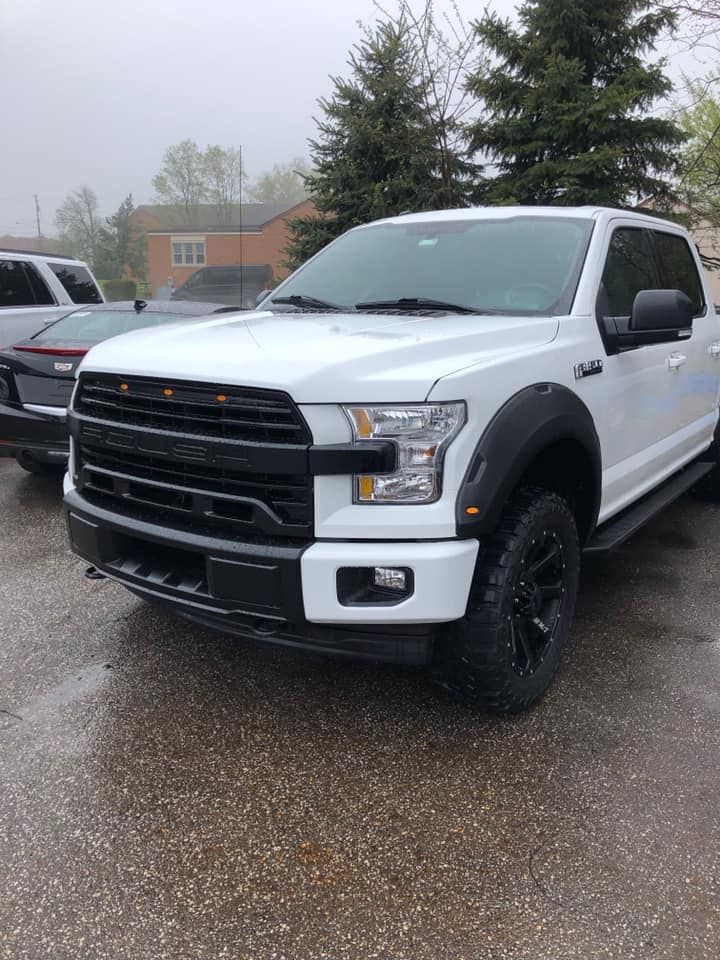 A white ford f150 truck is parked in a parking lot.