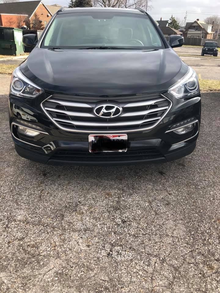 A black hyundai santa fe is parked in a parking lot.