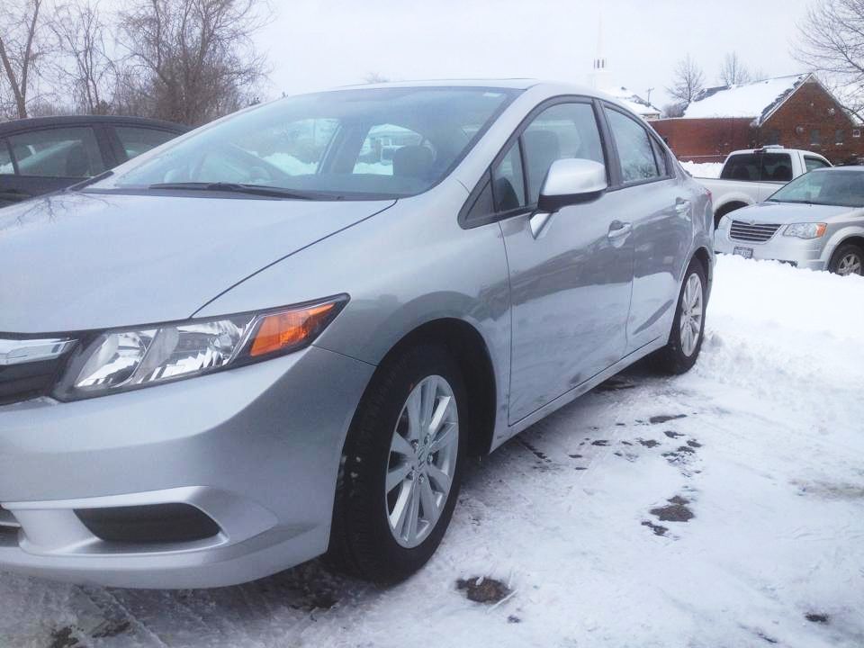 A silver honda civic is parked in the snow