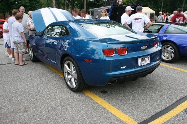 A group of people looking at a blue car with the hood up
