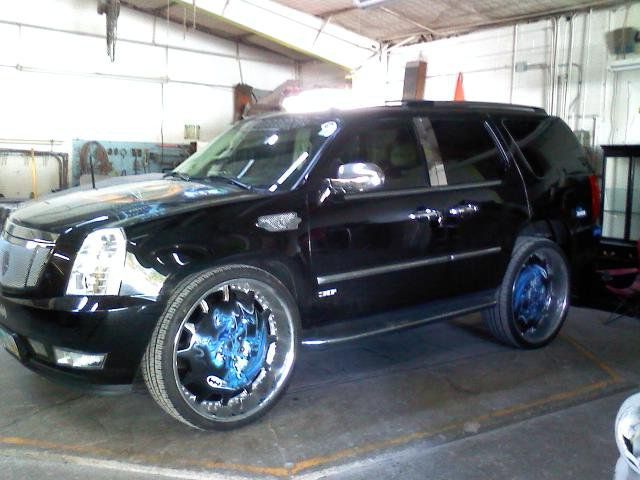 A black suv with blue wheels is parked in a garage