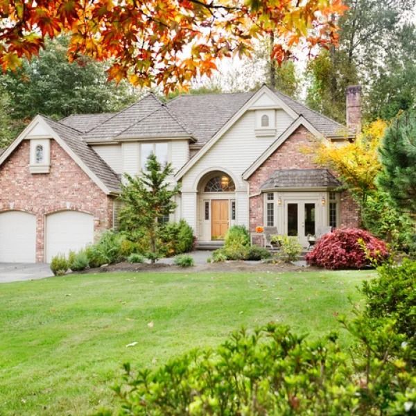 A large brick house with a lush green lawn in front of it.