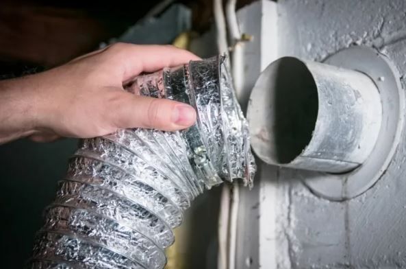 A person is holding a hose attached to a wall.