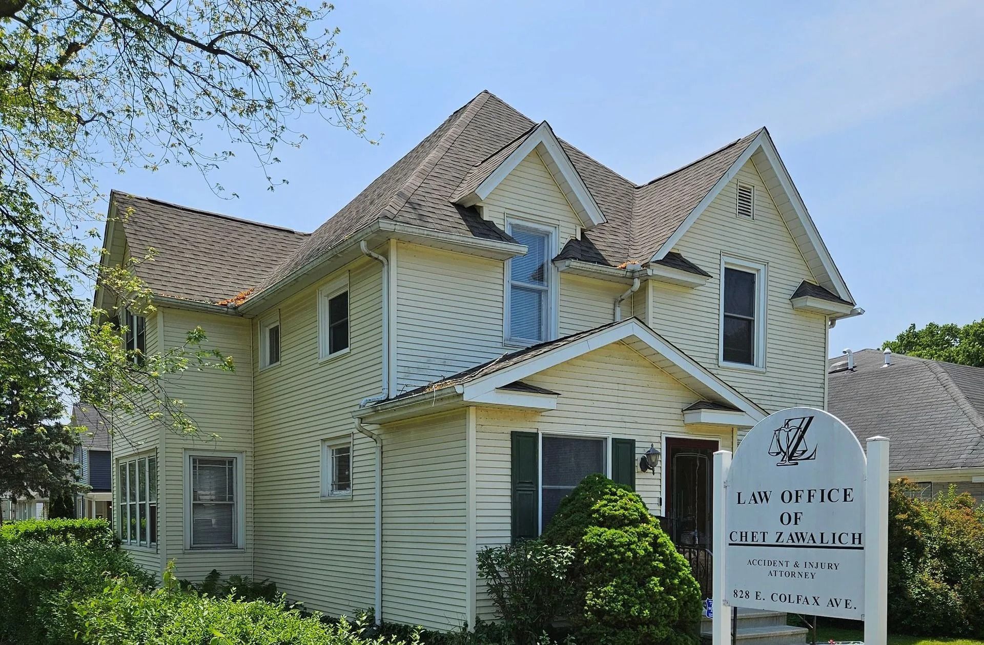 Cream-colored two-story house with a peaked roof and a sign for a medical office.