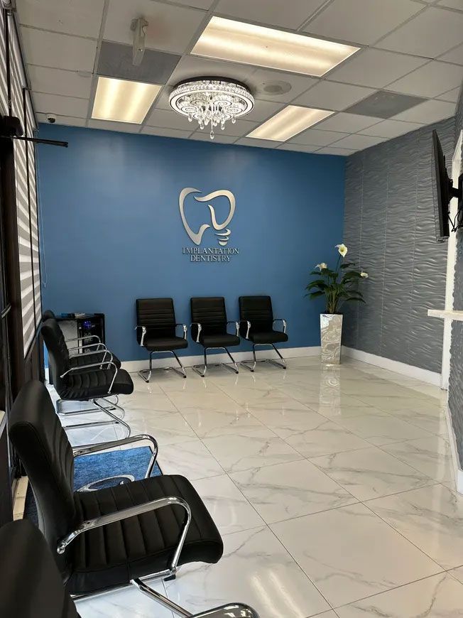 Dental office waiting room with blue walls, black chairs, and a dental logo.